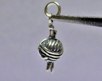 Puede incluir: Encanto de plata en forma de ovillo de lana con agujas de tejer.