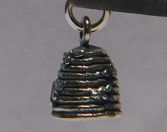 May include: Silver charm in the shape of a beehive with a loop for attaching to a bracelet or necklace.