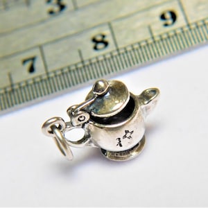 Peut inclure: Breloque en argent en forme de théière avec un couvercle. Le breloque a une petite boucle pour l'attacher à un bracelet ou un collier. Le breloque est marqué d'une étoile.