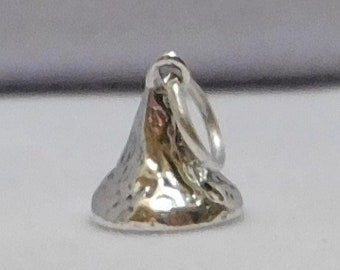 May include: A silver charm shaped like a Hershey's Kisses chocolate. The charm has a textured surface and a loop for attaching to a bracelet or necklace.