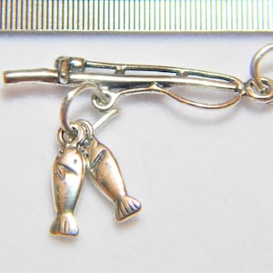May include: Silver charm of a fishing rod with two fish hanging from it.