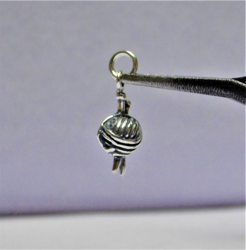 May include: Silver charm in the shape of a ball of yarn with knitting needles.
