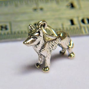 May include: A silver charm in the shape of a wolf, standing on all four paws with its head turned to the side. The charm has a detailed design and a loop at the top for attaching to a bracelet or necklace.