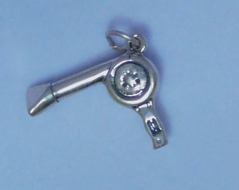 May include: Silver charm in the shape of a hair dryer. The charm has a detailed design and is perfect for a charm bracelet or necklace.