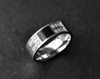 May include: A silver ring with a black inlay and two rows of small clear stones.