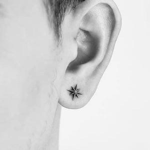 May include: A close-up of a person's ear with a small, silver star-shaped earring.