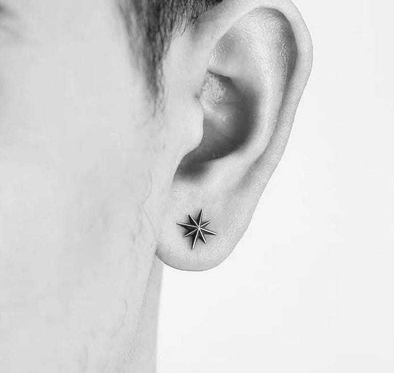 May include: A close-up of a person's ear with a small, silver star-shaped earring.