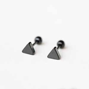 May include: A pair of black triangle stud earrings with a black post and a black ball on the back.