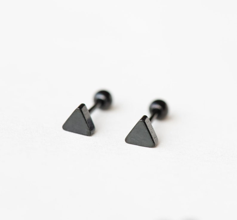 May include: A pair of black triangle stud earrings with a black post and a black ball on the back.