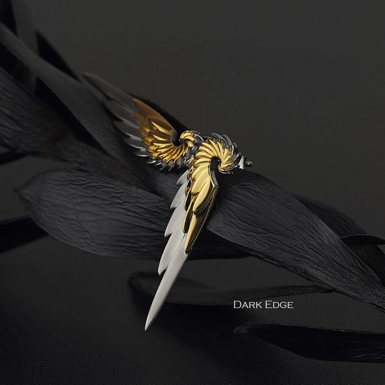 May include: A gold and silver wing-shaped earring with a detailed design. The earring is on a black background with the text "DARK EDGE".