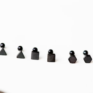 Op de afbeelding: Zes zwarte oorbel studs met verschillende geometrische vormen: driehoek, vierkant en zeshoek. De oorbel studs zijn gemaakt van metaal en hebben een zwarte afwerking.