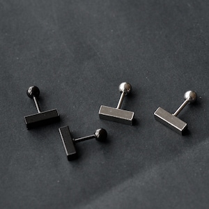 May include: Three silver and black stud earrings with a rectangular bar design. The earrings have a silver post and a black ball on the top.