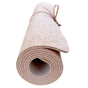 May include: Rolled up cork yoga mat with a brown leather strap tied around it.