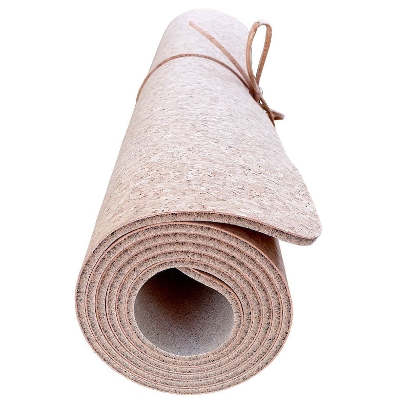 May include: Rolled up cork yoga mat with a brown leather strap tied around it.