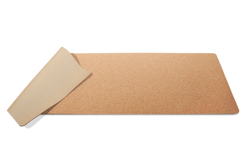 May include: A brown cork desk mat with a beige underside. The mat is rolled up on one side.