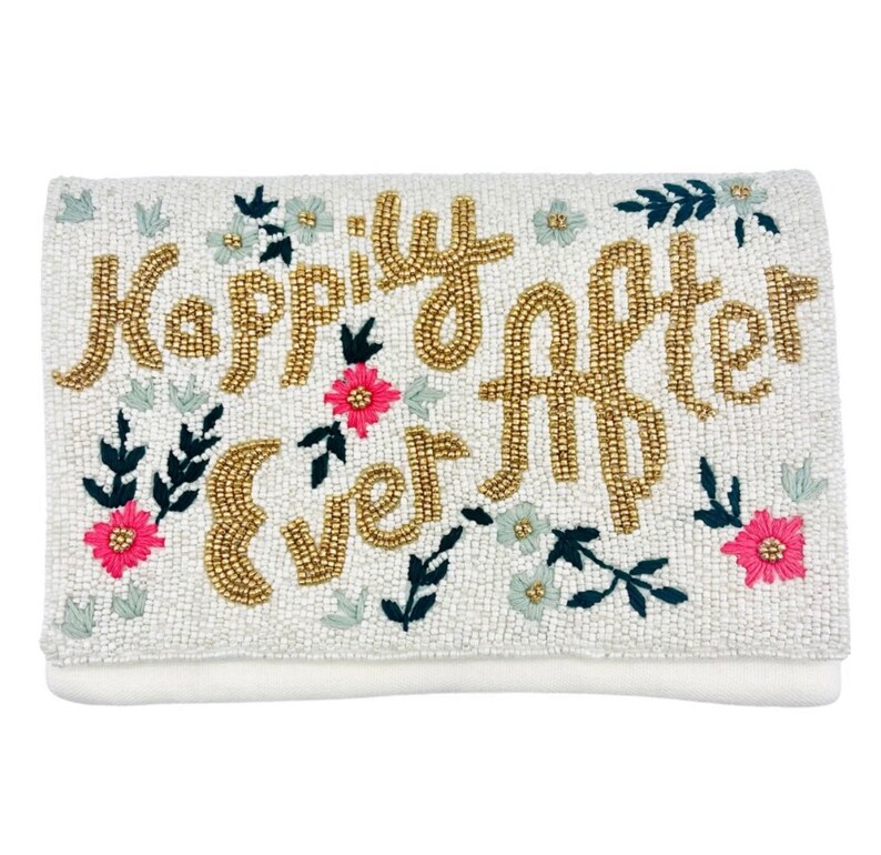 May include: White beaded clutch with gold lettering that reads "Happily Ever After" and floral embellishments.