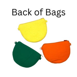 K&ouml;nnte beinhalten: Drei halbkreisf&ouml;rmige Taschen in Gelb, Gr&uuml;n und Orange, jeweils mit einem Rei&szlig;verschluss an der Oberseite und seitlichen Metallringen f&uuml;r Riemen. Der Text Back of Bags steht dar&uuml;ber. Diese Taschen haben eine einfarbige Stoffkonstruktion.
