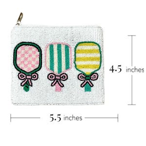 May include: A white beaded zippered pouch with three beaded paddle designs. The paddles are pink and white checkered, green and white striped, and yellow and white striped. The pouch measures 5.5 inches wide and 4.5 inches tall.