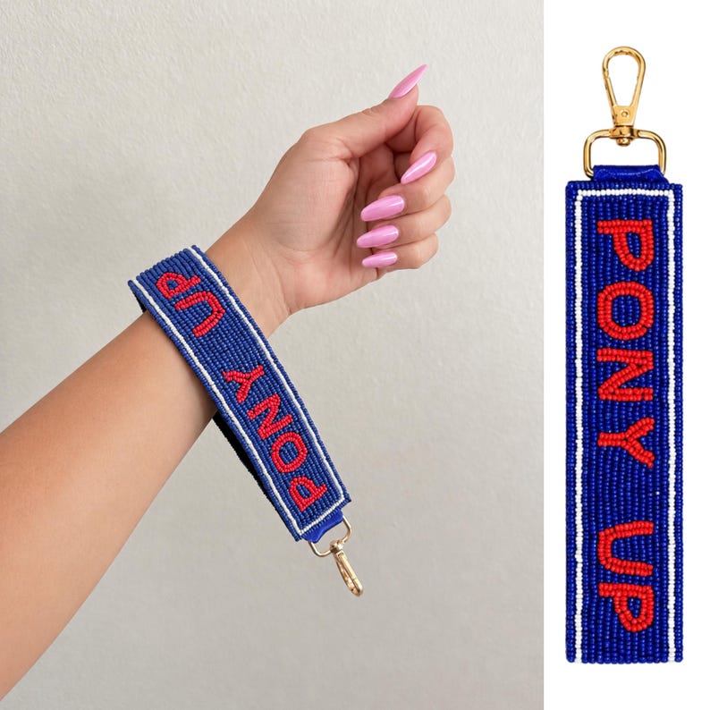 May include: A rectangular wristlet keychain featuring blue seed beads with the text PONY UP in red seed beads. The design includes white beaded borders and a gold-toned metal lobster clasp at the top. The strap is flexible and beaded on both sides.