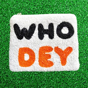 May include: A white beaded clutch bag with the words "WHO DEY" in black and orange beads.