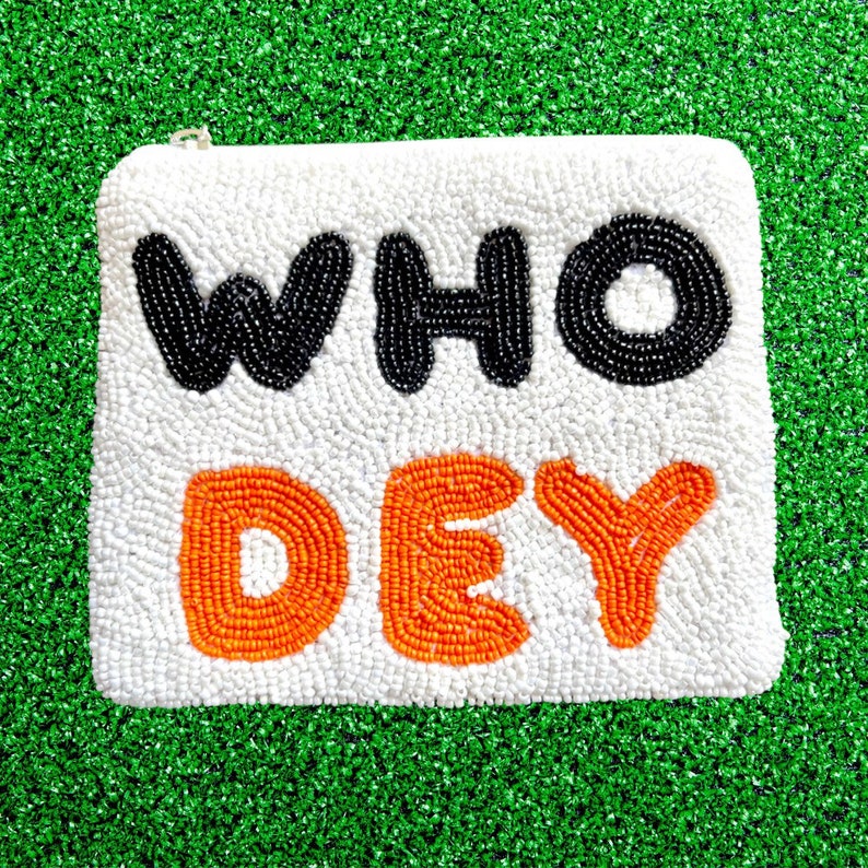 May include: A white beaded clutch bag with the words "WHO DEY" in black and orange beads.