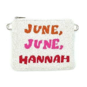 May include: A white beaded pouch with the words "JUNE, JUNE, HANNAH" in orange, pink, and red beads. The pouch has a silver zip and two silver rings on the sides. The pouch is square-shaped and appears to be made of small white beads.