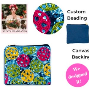 May include: A blue and white pouch with colorful beaded circles. The pouch has a canvas backing and a zipper closure. The text "Custom Beading" and "Canvas Backing" are visible in the image. The text "We designed it!" is in a pink circle.