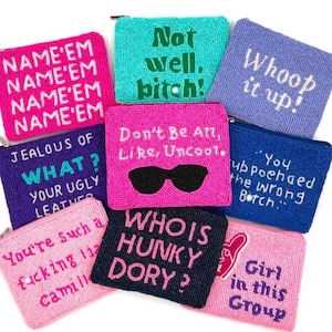 Puede incluir: Una colección de monederos de cuentas en varios colores, incluyendo rosa, azul y turquesa. Cada monedero presenta una frase o palabra diferente, como "Whoop it up!" y "Who is Hunky Dory?". Los monederos tienen cierre de cremallera.