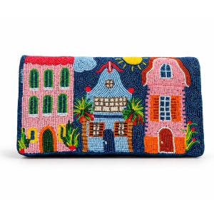 May include: A rectangular clutch bag featuring intricate beadwork depicting a colorful street scene with three buildings in shades of pink and blue, green palm trees, a yellow sun, and a dark blue background, all crafted with small glass beads.