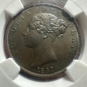 Könnte beinhalten: Eine bronzefarbene Münze von 1841, die das Profil einer Frau mit aufwendiger Frisur zeigt. Die Münze ist mit Text am Rand beschriftet, einschließlich des Jahres und der Worte "VICTORIA DEI GRATIA". Die Münze ist in einem Schutzhalter eingeschlossen.