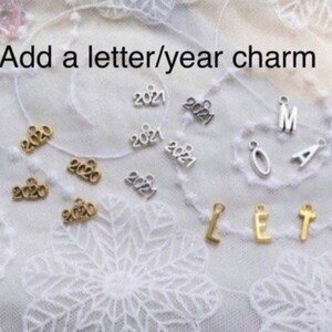 May include: Assortment of gold and silver charms featuring letters and the years 2020 and 2021.  Add a letter/year charm.