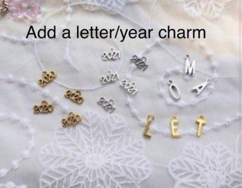 May include: Assortment of gold and silver charms featuring letters and the years 2020 and 2021.  Add a letter/year charm.