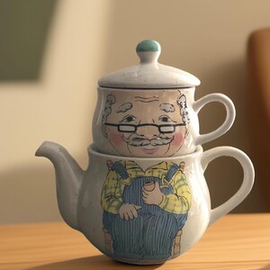 May include: A ceramic teapot featuring a cartoon illustration of a man with a moustache and glasses. The teapot has a lid with a matching design. The teapot is light blue with yellow, blue, and green accents.