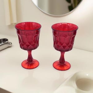 May include: Two red wine glasses with a diamond pattern. The glasses have a stem and a round base.