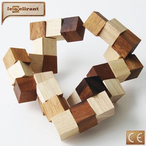 K&ouml;nnte beinhalten: Ein Holzpuzzle aus 16 kleinen W&uuml;rfeln, die jeweils zwei unterschiedlich farbige Seiten haben. Die W&uuml;rfel sind in einem Kreis angeordnet, wobei die unterschiedlich farbigen Seiten nach au&szlig;en zeigen. Das Puzzle ist aus hellem und dunklem Holz.