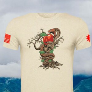 May include: A beige t-shirt with a graphic of a snake wrapped around a tree with a red apple. The snake's head is facing the apple. The t-shirt has a red, white, and blue American flag on the left sleeve and a red star on the right sleeve.