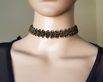 May include: A gold-toned chainmail choker necklace on a mannequin. The necklace is made of small, interconnected metal rings.