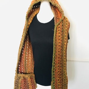 May include: A crocheted hooded scarf with a pocket in a mix of brown, orange, and green colors.
