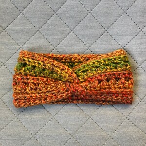 Può includere: Fascia per capelli fatta a mano, all'uncinetto con un design a torsione. La fascia presenta un mix di colori caldi, tra cui sfumature di marrone, arancione e verde. Il filato strutturato crea un accessorio accogliente ed elegante.