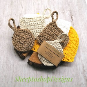 Könnte beinhalten: Eine Sammlung handgefertigter Häkelartikel in verschiedenen Formen und Farben, darunter Braun, Beige und Gelb. Jeder Artikel hat eine Schlaufe zum Aufhängen. Eine Visitenkarte mit dem Text "SheeptoshopDesigns" ist ebenfalls sichtbar.
