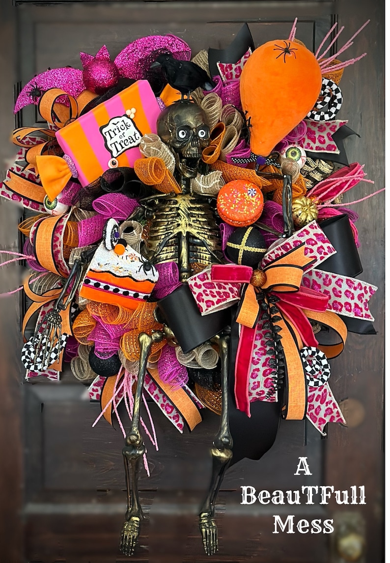 May include: A Halloween wreath featuring a skeleton, a black crow, a pink and orange candy box, a black and white checkerboard ribbon, a pink and black leopard print ribbon, and an orange balloon with a spider.