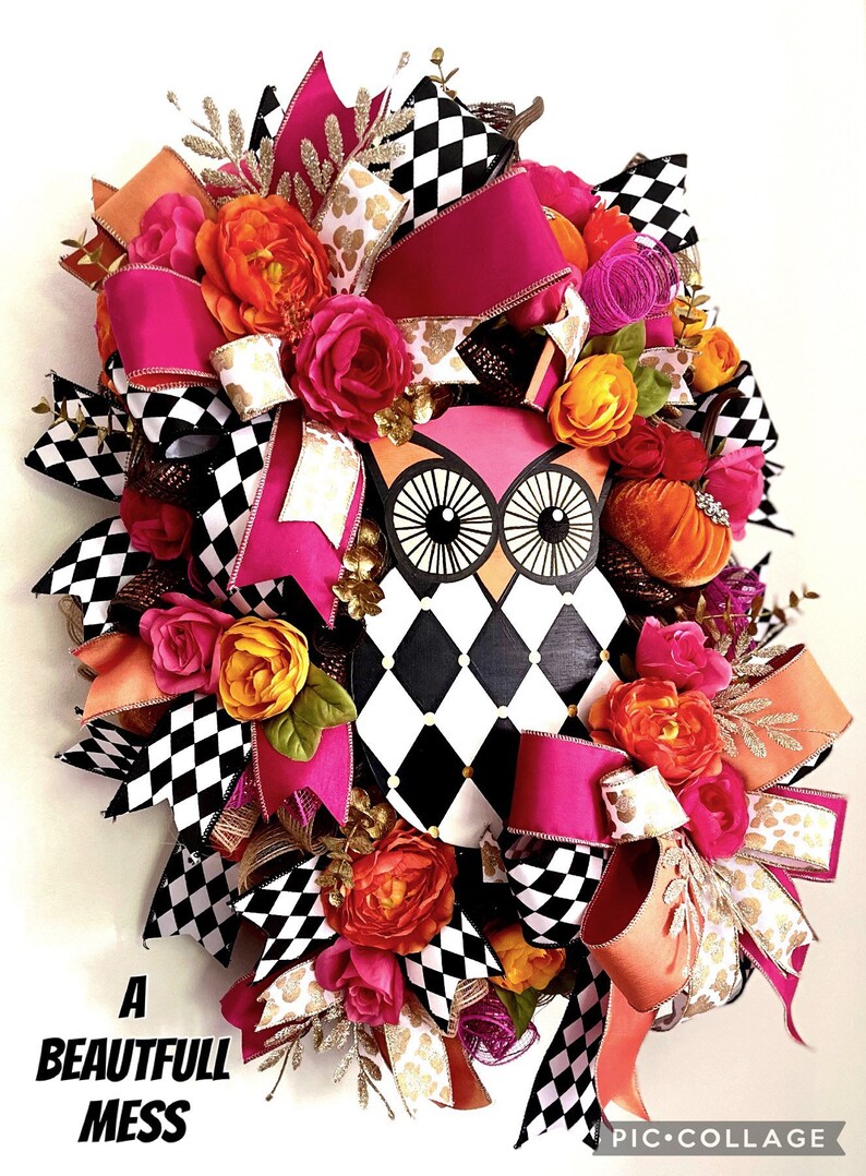 May include: A pink and black checkered owl wreath with pink, orange, and gold ribbon bows, and orange and pink flowers. The wreath has the text "A Beautiful Mess" on the bottom left corner.