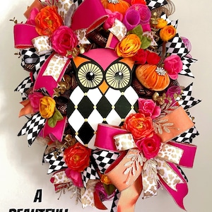 May include: A black and white checkered owl with pink accents, surrounded by pink, orange, and gold ribbon and floral accents. The wreath is decorated with small pumpkins and the text "A Beautiful Mess".