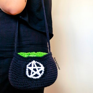 K&ouml;nnte beinhalten: Eine schwarze geh&auml;kelte Tasche mit einem wei&szlig;en Pentagramm-Design. Die Tasche hat ein gr&uuml;nes Futter und einen langen schwarzen Riemen. Die Tasche wird von einer Person getragen, die ein schwarzes Shirt tr&auml;gt.