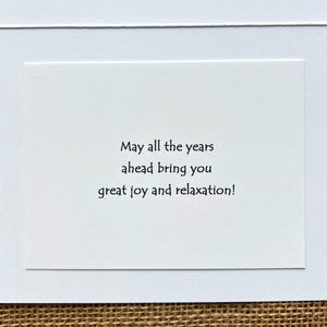 May include: A white greeting card with a white border and a white interior. The card's interior has the text: "May all the years ahead bring you great joy and relaxation!"