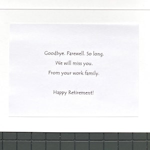 May include: A white retirement card with black text. The message reads: "Goodbye. Farewell. So long. We will miss you. From your work family. Happy Retirement!" The card is set against a dark gray tiled background.
