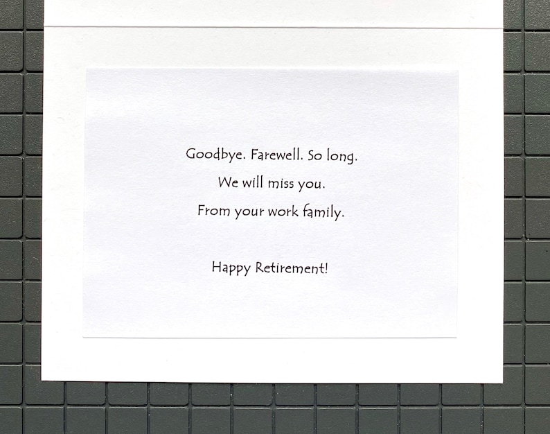 May include: A white retirement card with black text. The message reads: "Goodbye. Farewell. So long. We will miss you. From your work family. Happy Retirement!" The card is set against a dark gray tiled background.