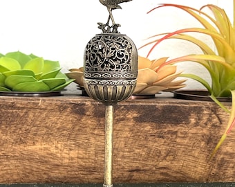 May include: An antique brass incense burner with a decorative filigree design. The burner features a detailed crane figurine on top. The base has an ornate, floral design. The incense burner is a decorative item.