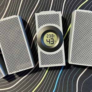 May include: A collection of white rectangular devices with a grid pattern, some with a blue accent. One device has a digital display showing 23.8&deg;C and 43%. The devices are arranged on a patterned surface.