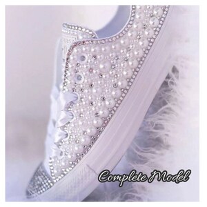 K&ouml;nnte beinhalten: Wei&szlig;e Canvas-Sneaker mit Perlen- und Strassbesatz. Die Schuhe sind mit Perlen und Strass besetzt und erzeugen so einen funkelnden Effekt.